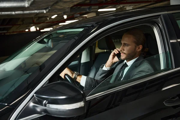 Appealing elegant professional in chic suit talking by phone behind steering wheel, business concept — Stock Photo