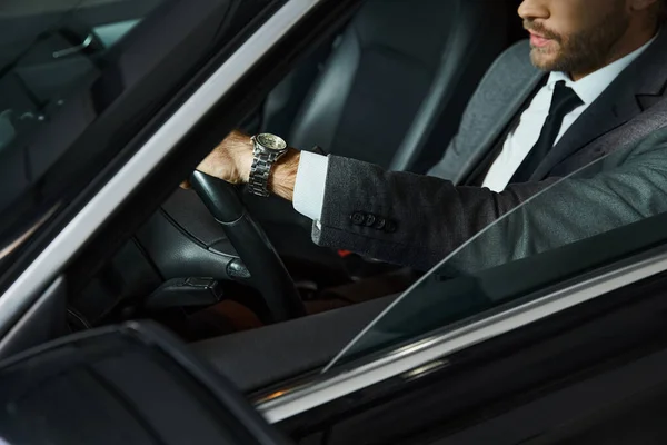 Cropped view of elegant man with tie and wristwatch behind steering wheel, business concept — Stock Photo