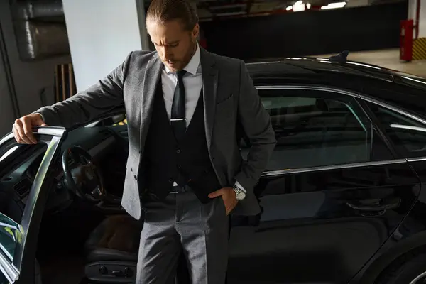 Atraente homem de negócios elegante com estilo dapper posando ao lado de seu carro com a mão no bolso — Fotografia de Stock