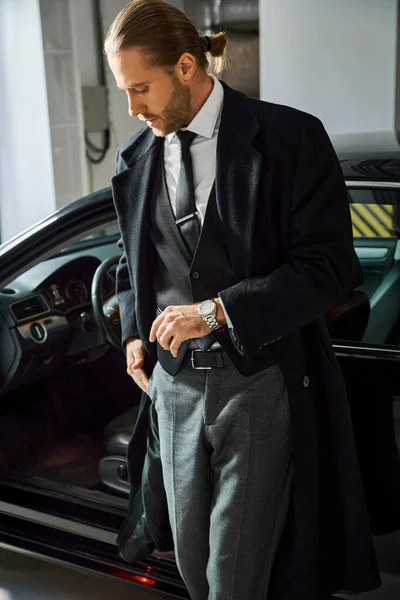 Привабливий чарівний бізнесмен в елегантному розумному вбранні позує поруч зі своєю машиною на парковці — стокове фото