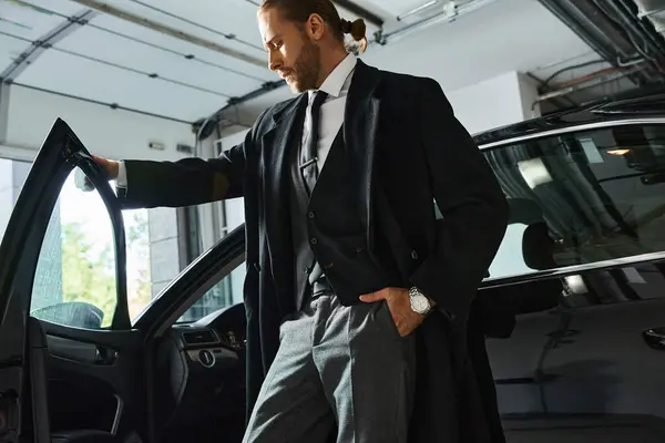 Homem elegante atraente em trajes inteligentes posando ao lado de seu carro com a mão no bolso, conceito de negócio — Fotografia de Stock