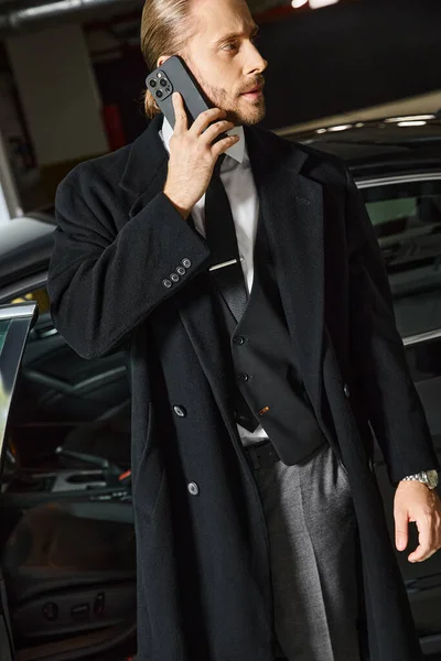 Handsome elegant man with ponytail and tie talking by phone on parking lot, business concept — Stock Photo