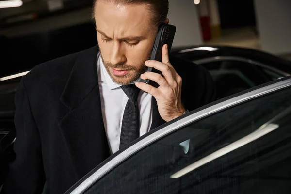 Homem de negócios de cabelos vermelhos de boa aparência em traje elegante elegante falando por telefone celular no estacionamento — Fotografia de Stock