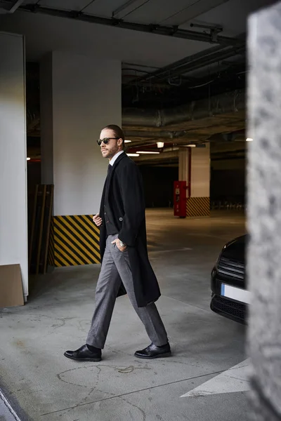 Handsome man in elegant smart attire with sunglasses walking on parking lot, business concept — Stock Photo