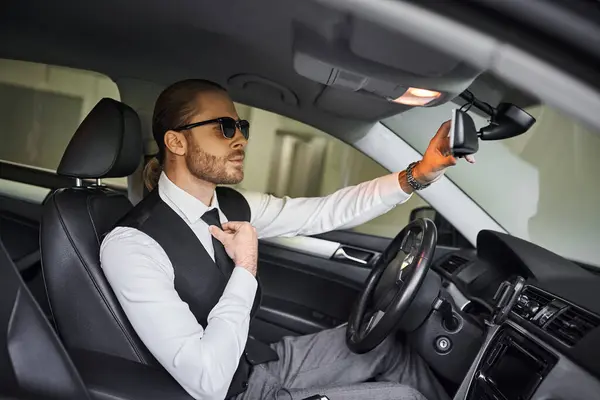 Atraente elegante profissional em colete preto com óculos de sol atrás do volante, conceito de negócio — Fotografia de Stock