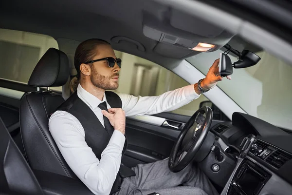 Ansprechender eleganter Profi in schwarzer Weste mit Sonnenbrille hinterm Lenkrad, Business-Konzept — Stockfoto