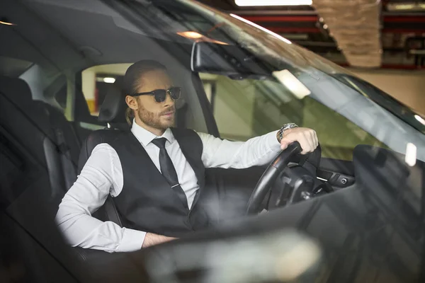 Bonito barbudo empresário com requintado dapper estilo com óculos de sol atrás volante — Fotografia de Stock