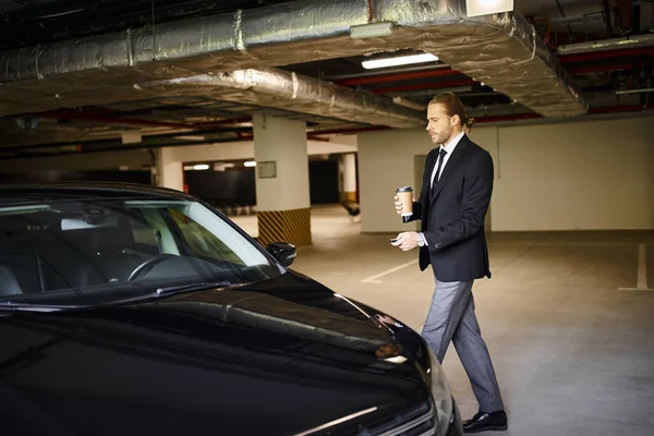 Attraktiver eleganter Mann mit Bart im schwarzen Anzug mit Kaffeetasse und Autoschlüssel, Geschäftskonzept — Stockfoto