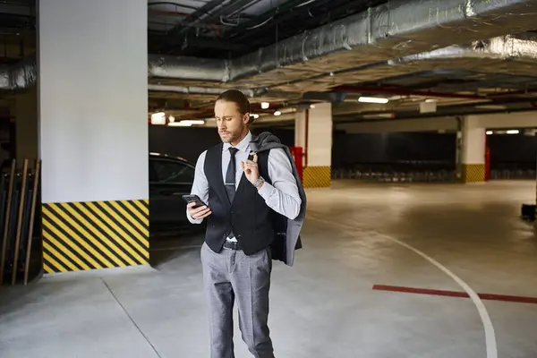 Homem de negócios elegante de boa aparência com estilo dapper requintado olhando para seu telefone no estacionamento — Fotografia de Stock