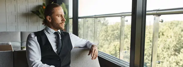 Attractive man in smart outfit sitting on sofa and looking out of window, business concept, banner — Stock Photo