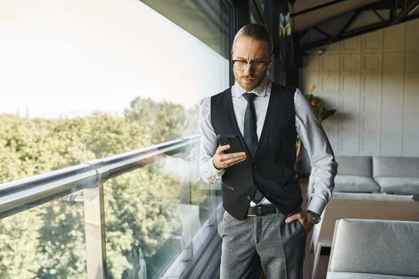 Atractivo hombre elegante con estilo elegante mirando el teléfono con la mano en el bolsillo, concepto de negocio - foto de stock