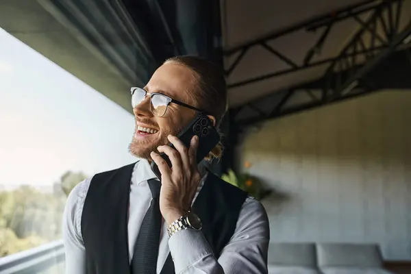 Alegre homem bonito em colete preto falando feliz por telefone perto da janela, conceito de negócio — Fotografia de Stock