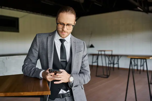 Элегантный бизнесмен в очках в шикарном костюме внимательно смотрит на свой мобильный телефон — стоковое фото
