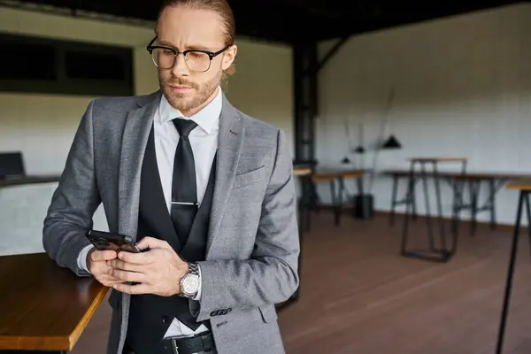 Bonito profissional em terno cinza inteligente olhando atentamente para o seu telefone móvel, conceito de negócio — Fotografia de Stock