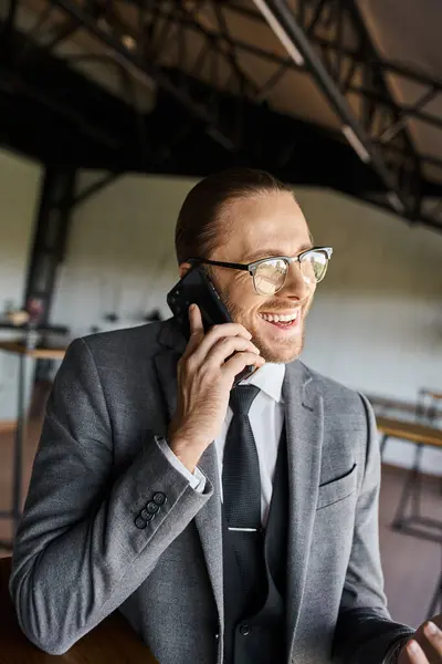 Fröhlich eleganter Geschäftsmann im schicken grauen Anzug, der aktiv telefoniert und glücklich lächelt — Stockfoto