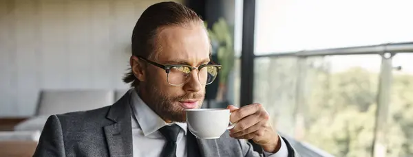Atraente empresário refinado com cabelo vermelho e óculos em terno inteligente beber chá, banner — Fotografia de Stock