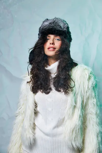 Bella donna con cappello peloso e abbigliamento bianco guardando la fotocamera su sfondo grigio, moda invernale — Foto stock