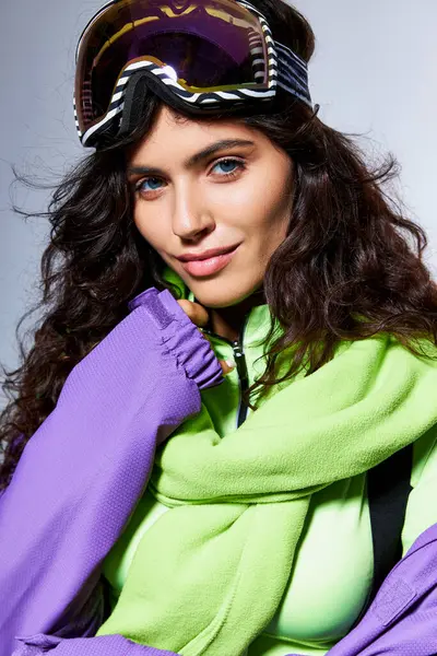Winter beauty, pretty woman with brunette hair posing in active wear with puffer jacket on grey — Stock Photo
