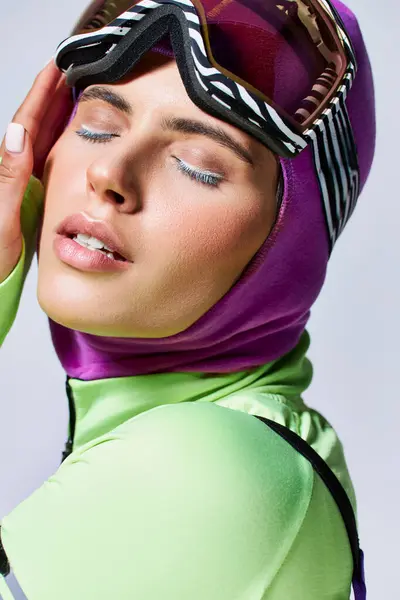 Close up retrato de mulher em roupas de esqui de inverno com balaclava na cabeça tocando rosto em cinza — Fotografia de Stock