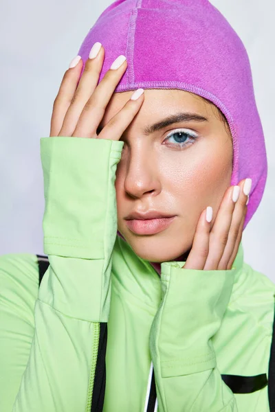 Portrait of beautiful woman with blue eyes posing in warm ski mask and active wear on grey backdrop — Stock Photo
