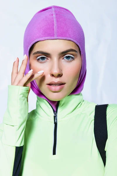 Ritratto di bella donna con occhi azzurri in posa con maschera da sci e abbigliamento attivo su sfondo grigio — Foto stock