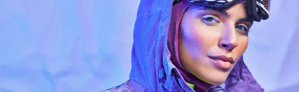 Зимний плакат, молодая женщина в лыжной маске, googles и теплый пиджак глядя на камеру на синем фоне — стоковое фото