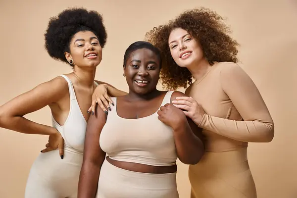 Multiethnisch kurvige und körperbetonte Frauen in Unterwäsche auf beigem Hintergrund, natürliche Plus-Size-Schönheit — Stock Photo