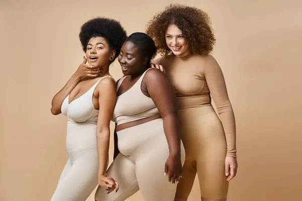 Alegre multiétnica más tamaño de las mujeres en ropa interior posando sobre fondo beige, confianza en sí mismo y encanto - foto de stock