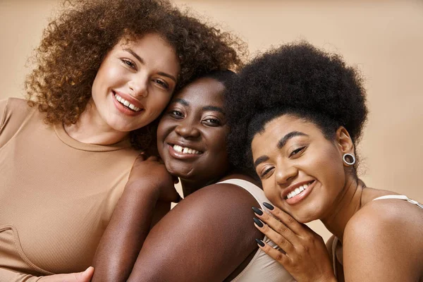 Diverse multiracial body positive women in underwear smiling on beige backdrop, plus size beauty — Stock Photo