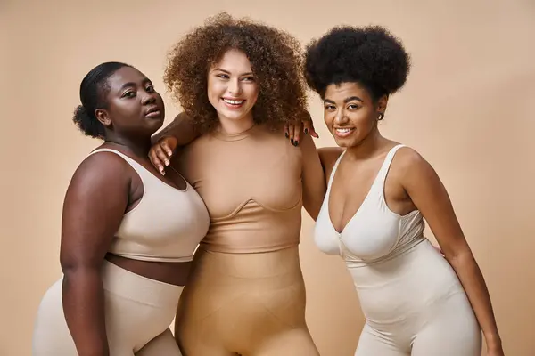 Diversas mulheres positivas corpo multirracial em roupa interior sorrindo em pano de fundo bege, além de beleza tamanho — Fotografia de Stock