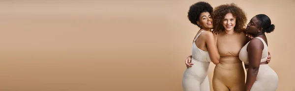 Alegre afro-americana mulher saindo da língua perto feliz mais tamanho namoradas no bege, banner — Fotografia de Stock