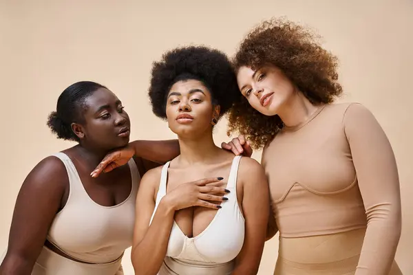 Mulheres multiétnicas confiantes e charmosas em roupa interior em pano de fundo cinza, beleza natural plus size — Fotografia de Stock