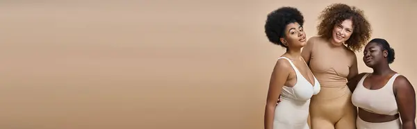 Felice multietnico plus size fidanzate in lingerie in posa su sfondo beige, corpo positivo, banner — Foto stock