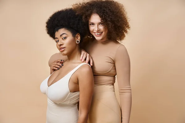 Corps multiculturel souriant femmes positives en sous-vêtements debout sur beige, beauté naturelle plus la taille — Photo de stock