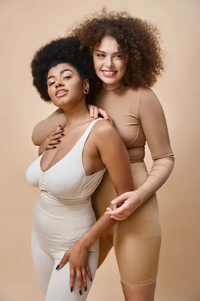 Cheerful multicultural body positive girlfriends on beige backdrop, natural plus size beauty — Stock Photo