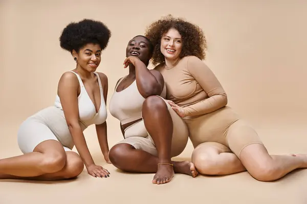 Heureux corps multiracial femmes positives en lingerie posant sur fond beige, beauté naturelle — Photo de stock