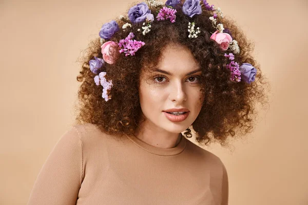 Retrato de mulher feliz com flores coloridas no cabelo sorrindo para a câmera em bege, beleza natural — Fotografia de Stock