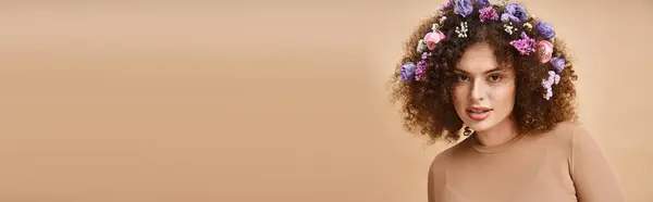 Портрет счастливой женщины с красочными цветами в волосах, смотрящей в камеру на бежевом, горизонтальном баннере — стоковое фото