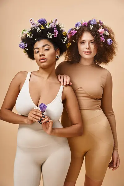 Multiracial Körper positive Frauen in Dessous mit bunten Blumen im Haar auf beige, plus Größe Schönheit — Stockfoto