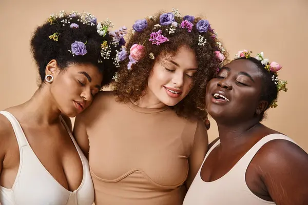 Multirassische Plus-Size-Frauen in Dessous mit bunten Blumen im Haar und geschlossenen Augen auf beige — Stockfoto
