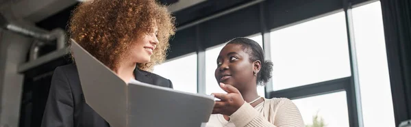 Donna d'affari multietnica creativa che discute la start-up vicino alla cartella con documenti in ufficio, banner — Foto stock