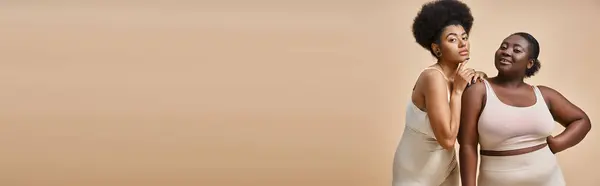 Curvy modèles féminins afro-américains en sous-vêtements regardant la caméra sur beige, bannière horizontale — Photo de stock