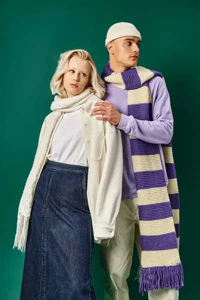 Couple in winter attire, stylish man in putting hand on shoulder of young woman on turquoise — Stock Photo