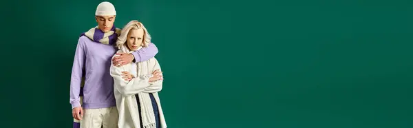 Tall and stylish man hugging blonde woman in winter attire on turquoise backdrop, banner — Stock Photo