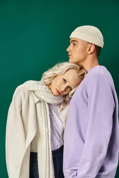 Beautiful woman in trendy winter attire putting head on shoulder of tall man on turquoise backdrop — Stock Photo