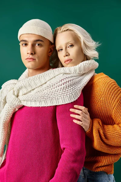 Pretty couple in sweaters sharing white scarf and posing together on turquoise, winter fashion — Stock Photo