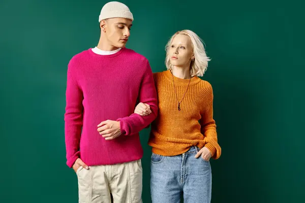 Fashionable couple in winter outfits posing with hands in pockets on turquoise background — Stock Photo