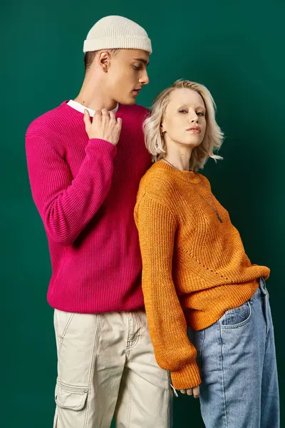 Stylish young couple in winter sweaters posing and looking at camera on turquoise background — Stock Photo