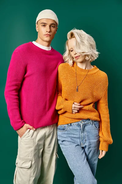 Junge blonde Frau posiert mit hübschem Freund im Pullover auf türkisfarbenem Hintergrund, junges Paar — Stockfoto