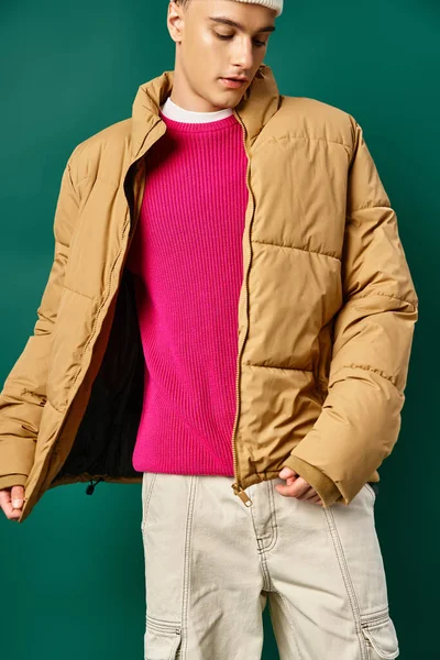 Hombre joven en gorro sombrero y chaqueta hinchable de invierno posando sobre fondo turquesa, tendencias de invierno - foto de stock
